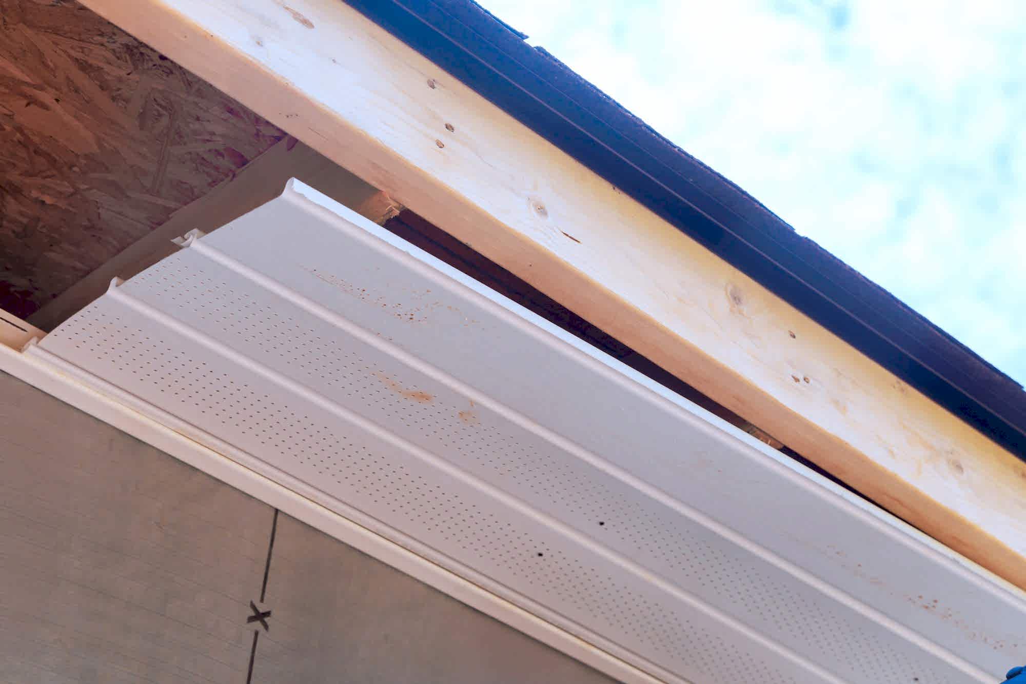 Worker installation of upvc soffit boards on roof corners ceiling rafters a house